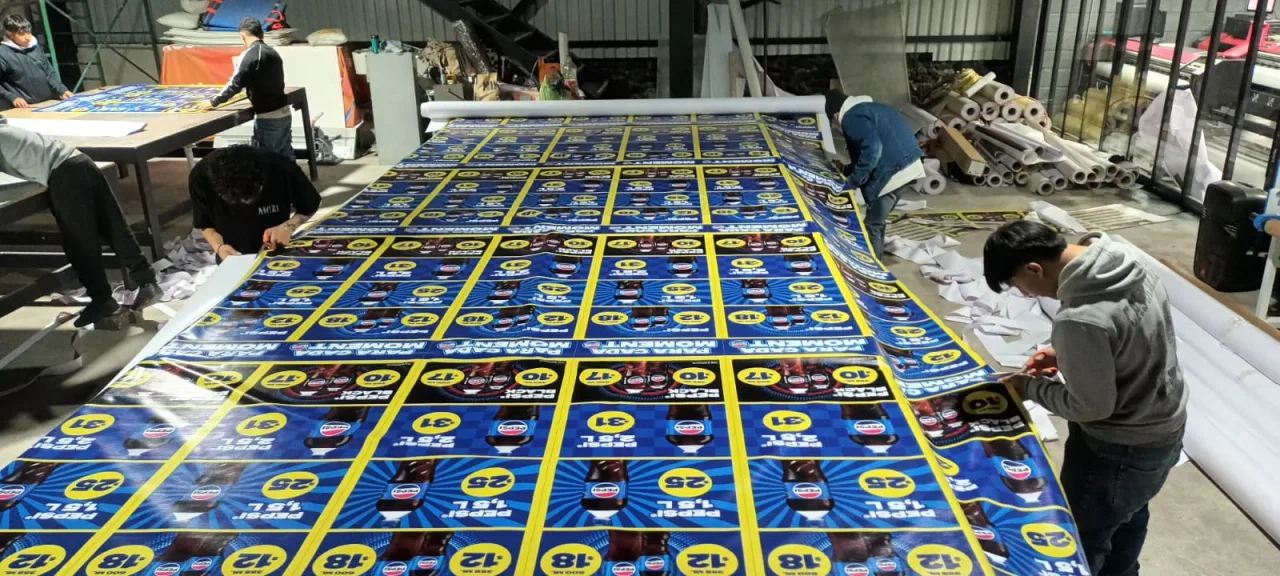 Equipo de producción realizando acabados sobre material impreso de gran formato